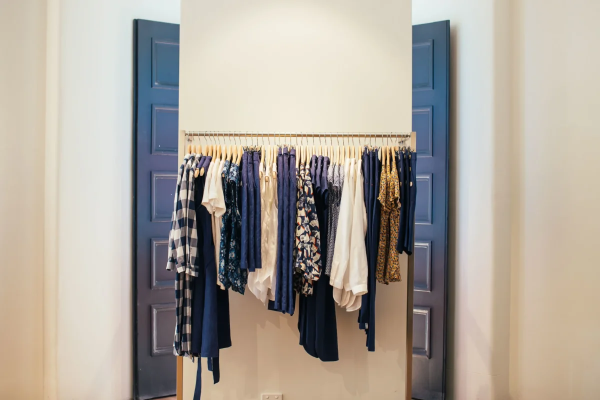 Organized clothing rack with shirts, trousers and patterned garments on wooden hangers
