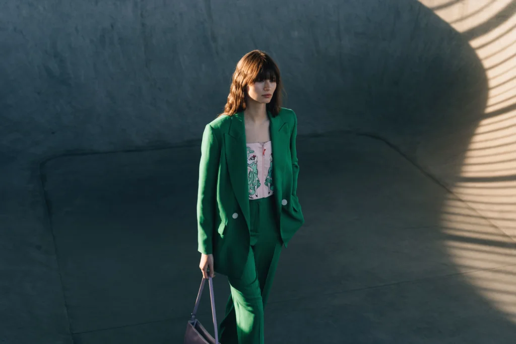 Woman wearing a green tailored blazer and matching trousers with a patterned top