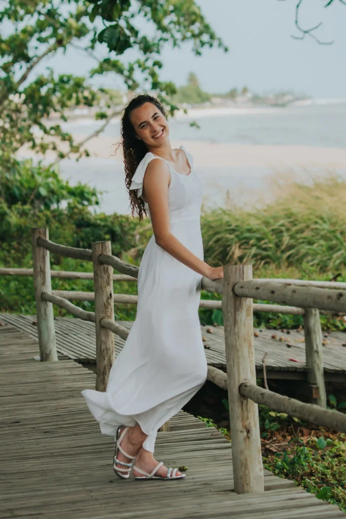 Woman wearing a long white sleeveless dress with sandals near the beach