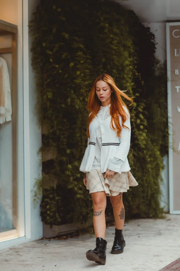 Woman wearing a white cardigan, checked mini skirt and black lace-up boots