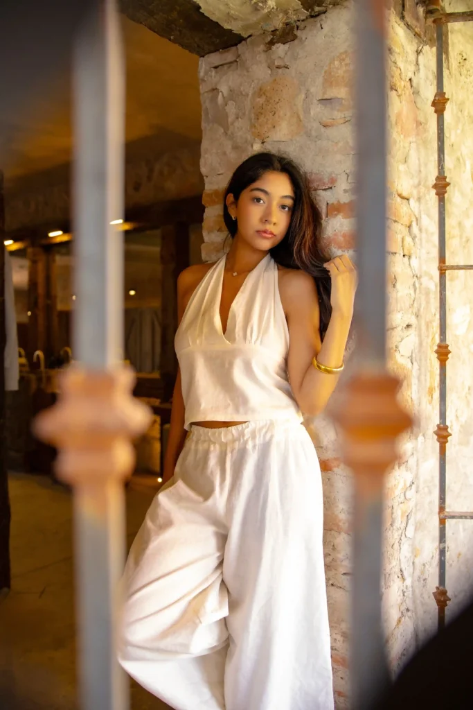 Woman wearing a white halter-neck top with loose white wide-leg trousers