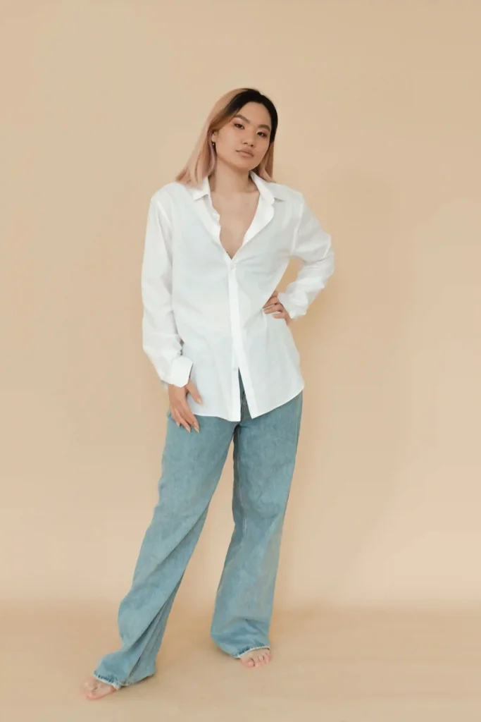 Woman wearing an oversized white button-down shirt with relaxed light-blue jeans